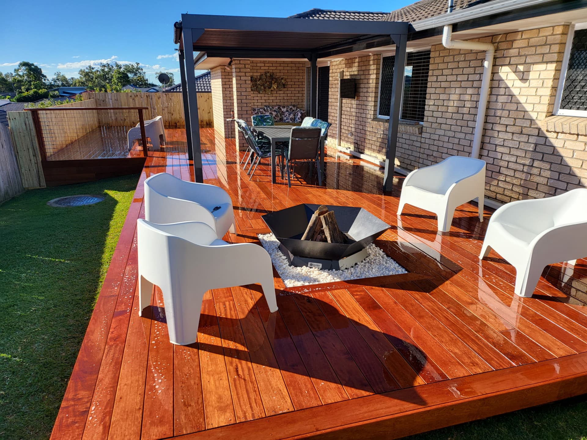 Freshly oiled hardwood deck with fire pit and covered patio built by Colonel Fix-A-Lot